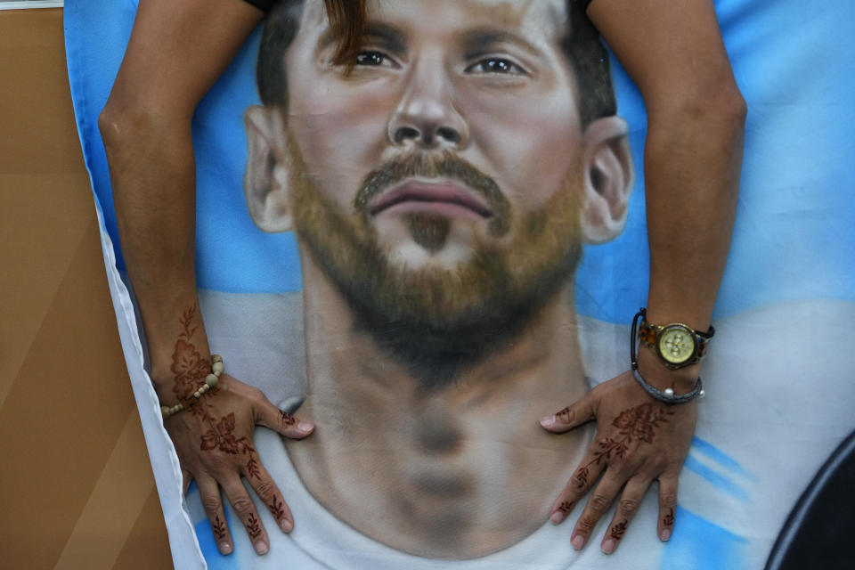 An Argentinian places a poster of their star player Lionel Messi's before the World Cup final soccer match between Argentina and France at the Lusail Stadium in Lusail, Qatar, Sunday, Dec. 18, 2022. (AP Photo/Petr David Josek)