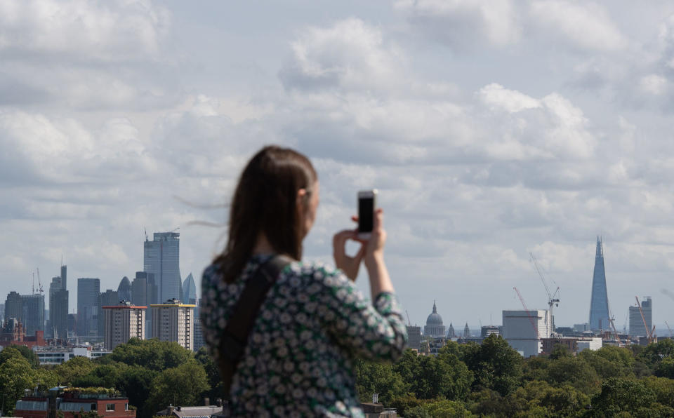 A woman takes a photo of the London skyline from Primrose Hill in London on Saturday (Picture: PA)