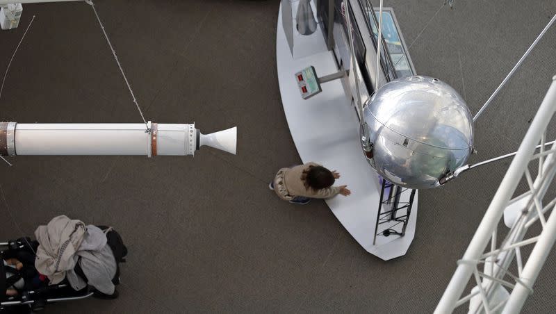 A child climbs below a Sputnik 1 test satellite, right, most likely manufactured by the Academy of Sciences of the USSR and one of only two known to exist, on display at the Museum of Flight on Oct. 2, 2017, in Seattle. At left is a full-size model of Explorer 1, a U.S. satellite developed in response to the Soviet satellite and launching the space race.