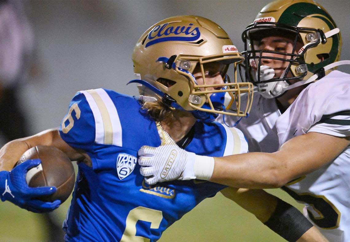 Clovis High’s Tyler Cheney, left, tries to cut back on a carry against Garces High’s Austyn Hernandez, right, Thursday, Aug. 17, 2023 in Clovis. ERIC PAUL ZAMORA/ezamora@fresnobee.com