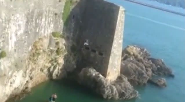 The boy in mid-air as he jumps off the cliff near rocks. Photo: YouTube