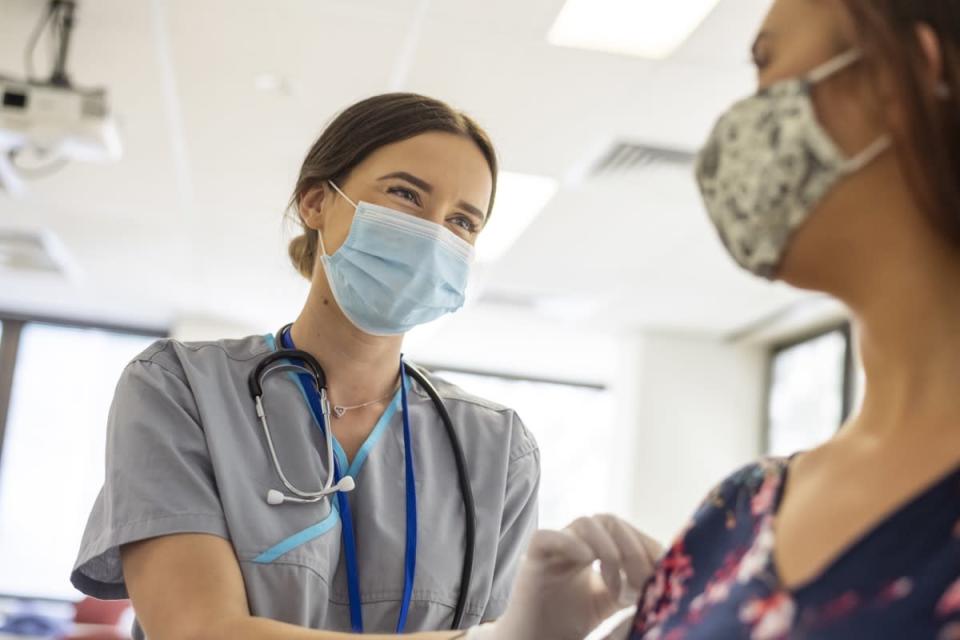 Friendly nurse preps patient prior to COVID-19 vaccine shot.