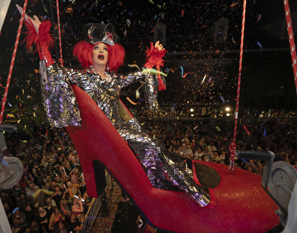 In this photo provided by the Florida Keys News Bureau, drag performer Gary Marion portraying "Sushi" hangs in an oversized replica of a women's red high heel over Duval Street late Saturday, Dec. 31, 2022, at the Bourbon St. Pub Complex in Key West, Fla. The Red Shoe Drop is a Key West tradition and one of several warm-weather Florida Keys takeoffs on New York City's Times Square ball drop marking the start of the new year. It is to be Marion's 25th time "dropping" in the shoe and he has announced he will pass the role on to a new drag performer. (Rob O'Neal/Florida Keys News Bureau via AP)