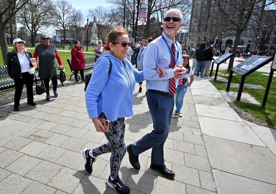 Douglas Lord, a director of library services at the Worcester Public Library, escorts Carmen Fitzpatrick of Rochdale to get her eclipse viewing glasses at Worcester Town Common. Fitzpatrick was first in line and had been waiting since 8 a.m.