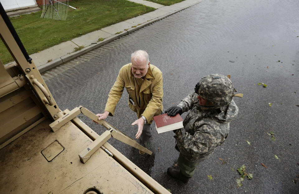 Maryland National Guard Sgt. Zachary Greene holds a bible for Harold "Doc" Sterling as he prepares to climb the ladder into a National Guard truck to be evacuated from his home after the effects of superstorm Sandy Tuesday, Oct. 30, 2012, in Crisfield, Md. (AP Photo/Alex Brandon)