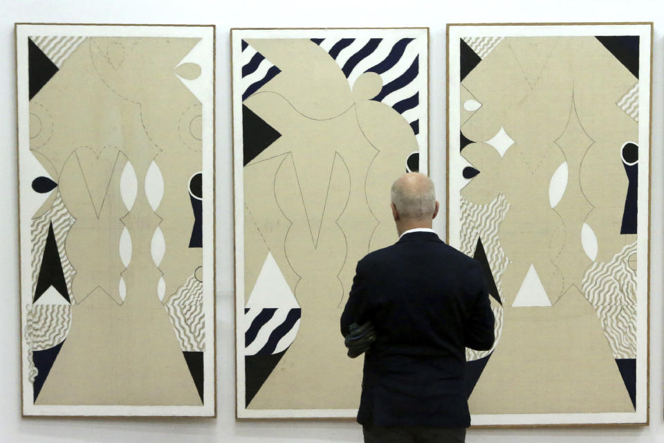 A man stands in front of a painting during an exhibition of culturally significant paintings that were recently exchanged as part of an effort to boost confidence between the ethnically divided island nation's two communities, at the Ledra Palace Hotel inside the UN controlled buffer zone in divided capital Nicosia, Cyprus, Monday, Feb. 3, 2020. Cyprus' President Nicos Anastasiades and the leader of the ethnically divided island's breakaway Turkish Cypriots Mustafa Akinci attended the exhibition. (AP Photo/Petros Karadjias)