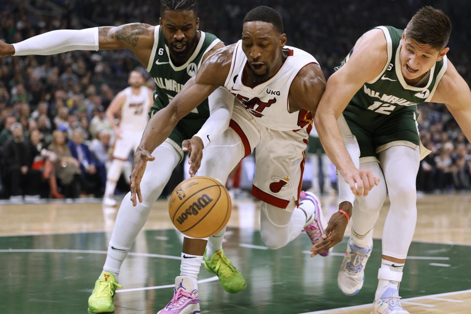 Miami Heat center Bam Adebayo, center, and Milwaukee Bucks' Wesley Matthews, left and Grayson Allen reach for the ball during the first half of Game 5 in a first-round NBA basketball playoff series Wednesday, April 26, 2023, in Milwaukee. (AP Photo/Jeffrey Phelps)