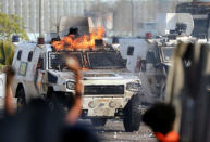 Demonstrators react in front of a burning military vehicle during clashes with security forces following a rally against the government of Venezuela's President Nicolas Maduro and to commemorate May Day in Caracas, Venezuela May 1, 2019. REUTERS/Manaure Quintero