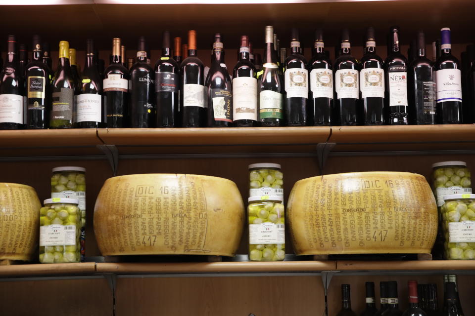 Wheels of parmesan cheese are on sale with spirits in a deli in Rome, Thursday, Oct. 3, 2019. The U.S. had prepared for Wednesday's ruling and already drawn up lists of the dozens of goods it would put tariffs on. They include EU cheeses, olives, and whiskey, as well as planes, helicopters and aircraft parts in the case _ though the decision is likely to require fine-tuning of that list if the Trump administration agrees to go for the tariffs. (AP Photo/Alessandra Tarantino)