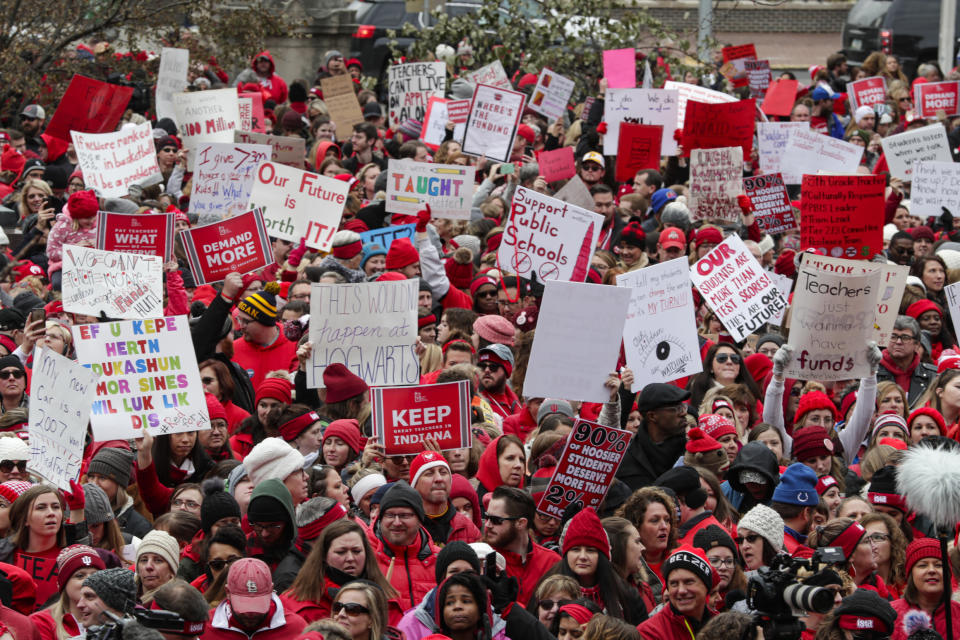 Thousands of Indiana teachers wearing red surround the Statehouse in Indianapolis, Tuesday, Nov. 19, 2019 for a rally calling for further increasing teacher pay in the biggest such protest in the state amid a wave of educator activism across the country. Teacher unions says about half of Indiana's nearly 300 school districts are closed while their teachers attend Tuesday's rally while legislators gather for 2020 session organization meetings.(AP Photo/Michael Conroy)