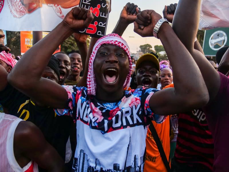 Supporters of presidential candidate Umaro Sissoko Embalo carry his picture and gesture along a road in Bissau