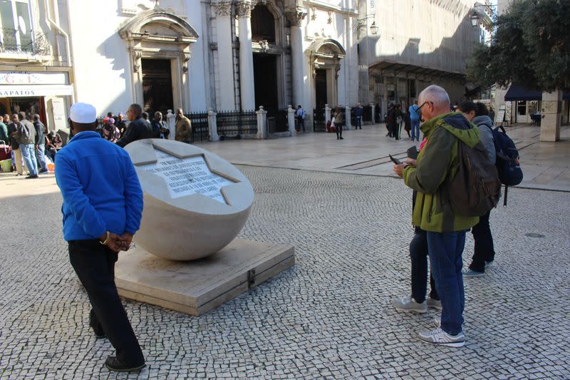 People stand next to a memorial marking the Jewish Massacre of 1506, in Lisbon