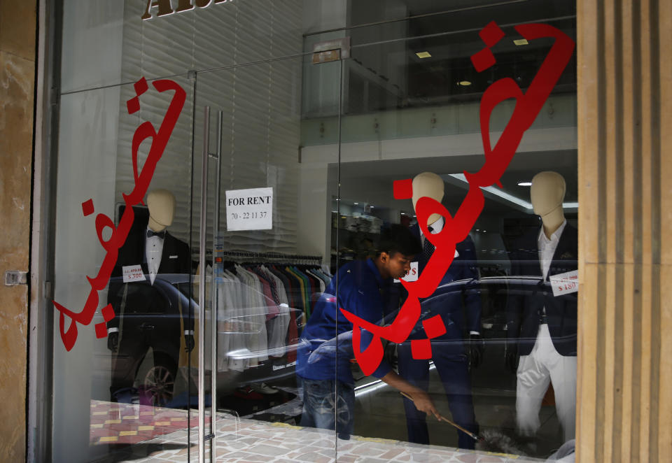 In this Thursday, July 18, 2019 photo, a worker cleans a display in shop with Arabic on the window that read: "Liquidation" and "the shop is for rent," in Hamra street, Beirut, Lebanon. As the economic crisis deepens in Lebanon, so has the public’s distrust in the ability of the old political class, widely viewed as corrupt and steeped in personal rivalries, to tackle major reform. Many fear a Greek-style bankruptcy, without the European Union to fall back on, and with a potentially more violent social unrest in the small country wedged between war-torn Syria and Israel. (AP Photo/Hussein Malla)