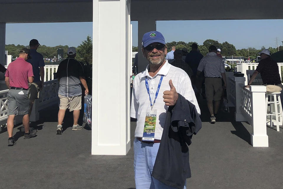 In this photo provided by Bob Van Wert, Tom Randele, whose real name according to authorities is Ted Conrad, stands for a photograph at an entrance to the 2018 U.S. Open Golf Tournament at Shinnecock Hills Golf Club, in Southampton, N.Y. According to authorities, Conrad, a former Ohio bank teller-turned-thief, lived for decades under a different name in suburban Boston. Conrad died in May 2021. (Photo/Bob Van Wert via AP)
