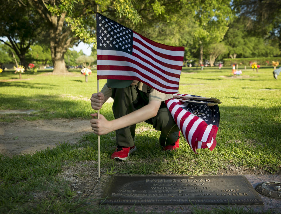 <p>Nathan Thom, 12, of BSA Troop 8787, places a U.S. flag on the grave of a veteran at the Cook-Walden Capital Parks Cemetery in Pflugerville, Texas, on Saturday May 26, 2018. For nearly 20 years, the scouts in the troop, which is chartered with VFW Post 8787, have gathered on the Saturday before Memorial Day to place about 5,000 flags on graves to honor veterans. (Photo: Jay Janner/Austin American-Statesman via AP) </p>