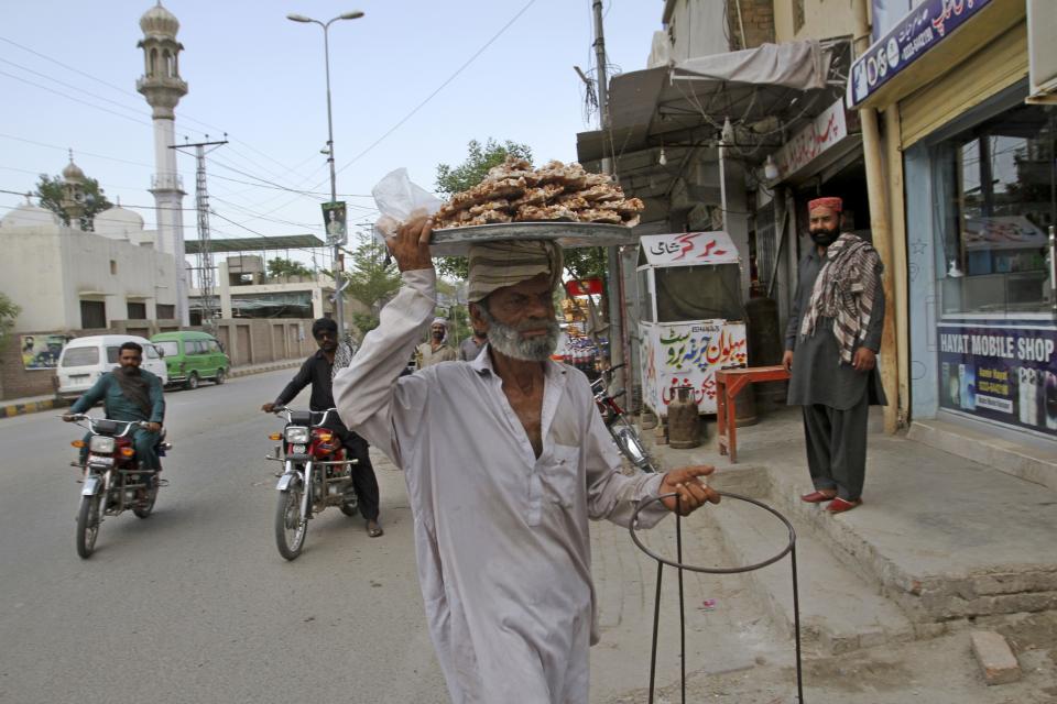 A man sells traditional sweets at a road in Rojhan town, in Rajanpur, a district of Pakistan's Punjab province, Sunday, May 21, 2023. Millions of acres of crops nationwide were destroyed by the waters last year, and a major international aid agency warned that the loss could be felt for years. (AP Photo/Asim Tanveer)