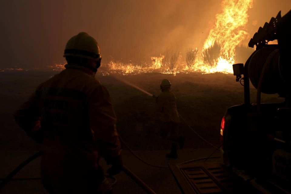 Firefighters work to stop a wildfire in Gouveia, in the Serra da Estrela mountain range, in Portugal on Thursday, Aug. 18, 2022. Authorities in Portugal said Thursday they had brought under control a wildfire that for almost two weeks raced through pine forests in the Serra da Estrela national park, but later in the day a new fire started and threatened Gouveia. (AP Photo/Joao Henriques)