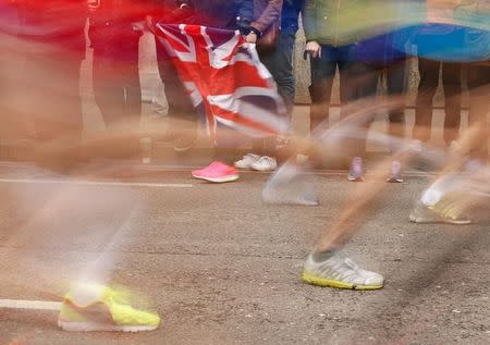 A spectator holds a Union Flag as runners make their way along Upper Thames Street during the London Marathon, April 26, 2015. REUTERS/Cathal McNaughton