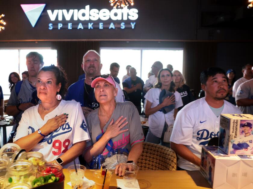 Dodger fans listen to the National Anthem at the speakeasy under the Right Field Pavilion at Dodger Stadium.