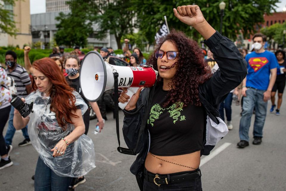 Cheyenne Osuala, right, holds a fist into the air as she chants into a megaphone on Friday evening as protesters marched to celebrate Breonna Taylor as well as mark the one-year anniversary of the historic Breonna Taylor protests. May 28, 2021