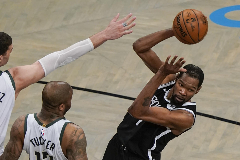 Brooklyn Nets' Kevin Durant, right, passes the ball away from Milwaukee Bucks' P.J. Tucker, center, and Brook Lopez, left, during the first half of Game 7 of a second-round NBA basketball playoff series Saturday, June 19, 2021, in New York. (AP Photo/Frank Franklin II)