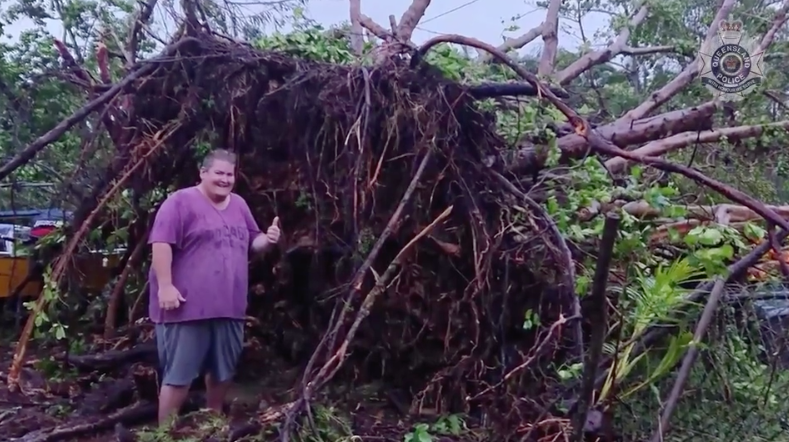 A resident poses with a fallen tree. Source: Queensland Police