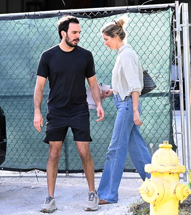 Joaquim Valente in a black shirt and shorts stands outside Gisele Bündchen's home as she walks behind him in jeans