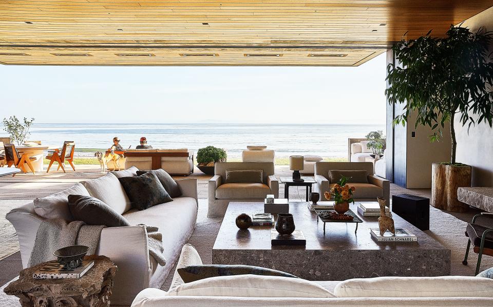 The living room opens to the terrace, where the Schwartzes lounge with the family dog. Custom armchairs in a de Le Cuona linen and bespoke cocktail table; 1960's Stig Lindberg lamp on side table.