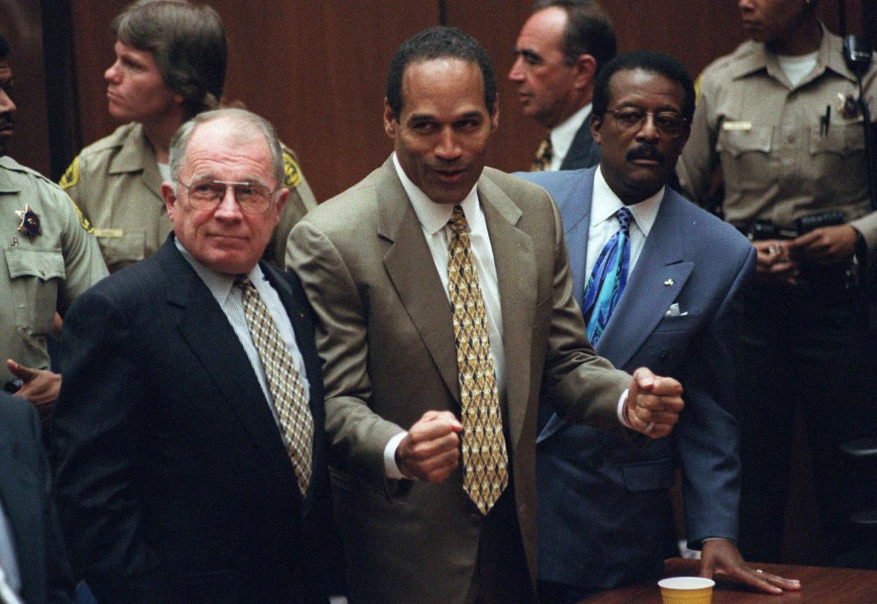 In this Oct. 3, 1995 picture, O.J. Simpson reacts as he is found not guilty of murdering his ex-wife Nicole Brown Simpson and her friend Ron Goldman. Three of his lawyers F. Lee Bailey (left),  Johnnie Cochran (right) and Robert Shapiro (rear, in profile) are also seen.