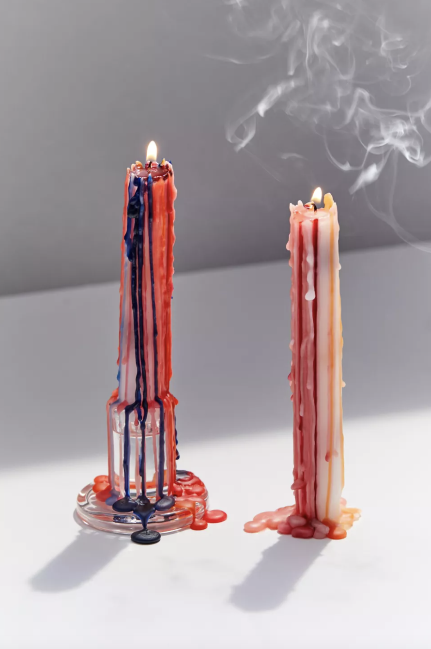 two multi-coloured drip candles with smoke coming off