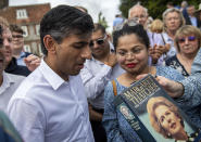 Britain's former Chancellor of the Exchequer Rishi Sunak is handed a copy of former prime minister Margaret Thatcher's book to sign, at an event at Manor Farm, in Ropley, as part of his campaign to be leader of the Conservative Party and the next prime minister, near Winchester, England, Saturday July 30, 2022. (Chris J Ratcliffe/PA via AP)
