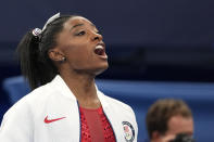 Simone Biles, of the United States, cheers for teammates after she exited the team final with apparent injury, at the 2020 Summer Olympics, Tuesday, July 27, 2021, in Tokyo. The 24-year-old reigning Olympic gymnastics champion Biles huddled with a trainer after landing her vault. She then exited the competition floor with the team doctor. (AP Photo/Ashley Landis)