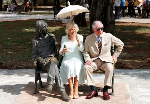 Charles and Camilla, Duchess of Cornwall sit on a bench next to a bronze statue of John Lennon in the eponymously named park in Havana - Credit: Reuters