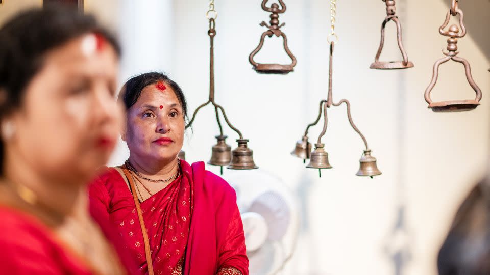 Bronze bells dangle from the ceiling, as two women look on during the inauguration of Itumbaha's new museum. - Pranab Joshi/Courtesy Itumbaha