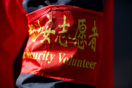 An armband identifies a woman as a public security volunteer as she keeps watch in a street ahead of the upcoming plenary session of National People's Congress (NPC), China's parliamentary body, in Beijing, China, March 1, 2018. REUTERS/Thomas Peter