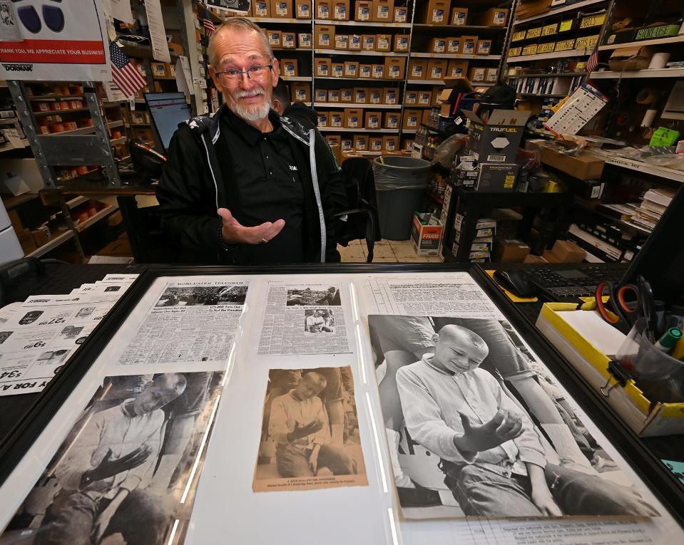 Michael Howlett, now 70, shows the hand that was grasped by President Lyndon Johnson on a trip to Worcester in 1964. Howlett, 10 years old at the time, later created a collage of news coverage of the day. Howlett is pictured at Advanced Auto Parts on Grafton Street, where he works.