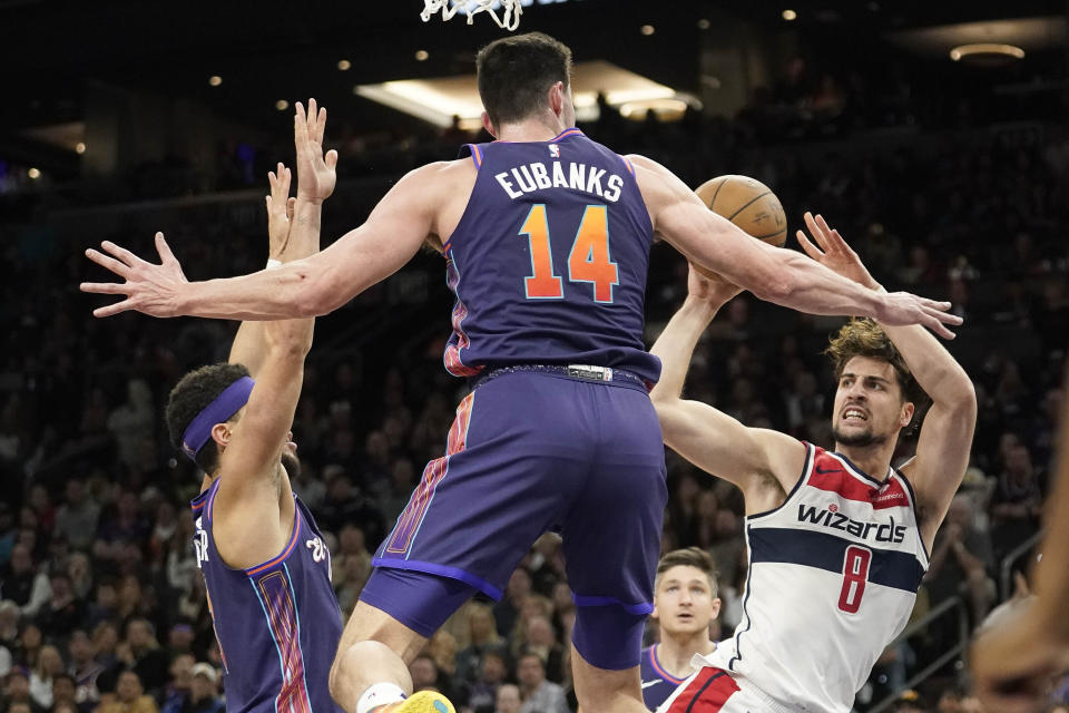 Washington Wizards' Deni Avdija (8) attempts to shoot as he is double-teamed by Phoenix Suns' Devin Booker, left, and Drew Eubanks (14) during the second half of an NBA basketball game in Phoenix, Sunday, Dec. 17, 2023. (AP Photo/Darryl Webb)