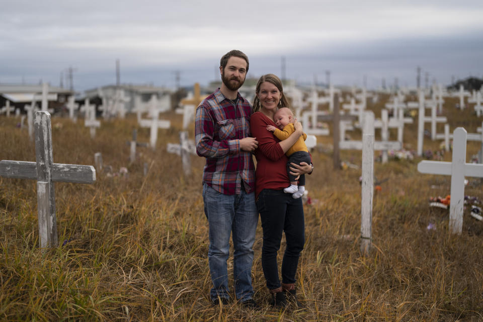 The Rev. Aaron Silco, and his wife, Anna, who are pastors at the Shishmaref Lutheran Church, stand for a photo with their two-month-old son, Aidan, in a cemetery next to the church in Shishmaref, Alaska, Tuesday, Oct. 4, 2022. "If they focus too much on that (on climate change), it will become too much of a weight, too much of a burden, because…there are birthday parties and there are funerals and there are sports events," Aaron Silco said. "There's still life happening despite all of the weight and the burden that climate change can cast upon this community." (AP Photo/Jae C. Hong)