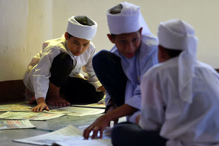 Madrasa students read a newspaper at Muhammadi Mosque before Friday prayers in Kota Bharu, Malaysia April 13, 2018. Picture taken April 13, 2018. REUTERS/Stringer