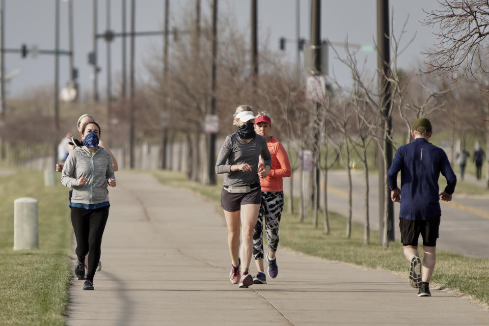 In this April 6, 2020 photo, joggers exercise in Omaha, Neb. As most governors have imposed stay-at-home orders that public health officials say are essential to slowing the spread of the new coronavirus, leaders in a handful of states have steadfastly refused to take the action, arguing it's unneeded and potentially harmful. (AP Photo/Nati Harnik)