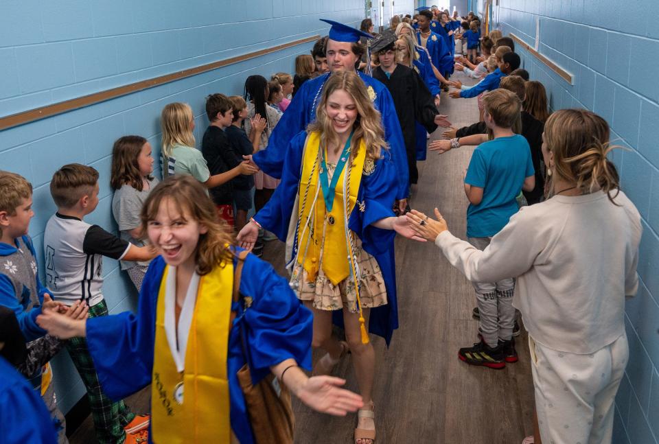 Otis A. Mason Elementary School students line the hallways of the school as former students, who are soon to be graduating high school seniors, march through the school wearing their cap and gowns on Wednesday, May 18, 2022.  