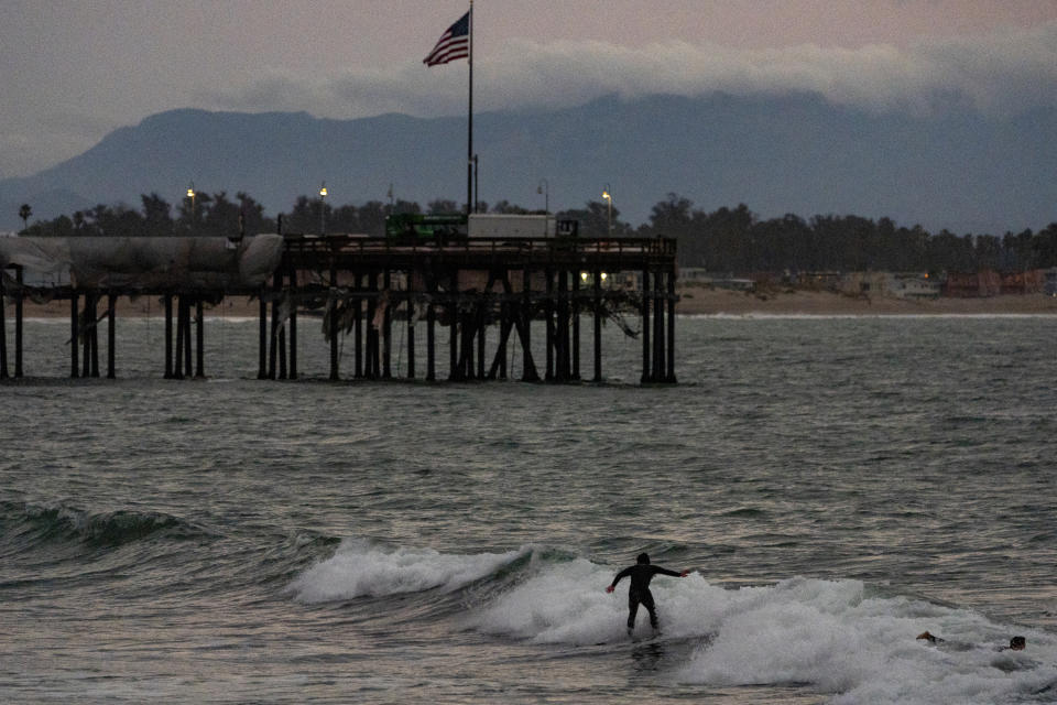 Surfers ride waves at sunset next to Ventura Pier, formerly known as the San Buenaventura Wharf, is seen ahead of storms in Ventura, Calif., Wednesday, Jan. 31, 2024. (AP Photo/Damian Dovarganes)