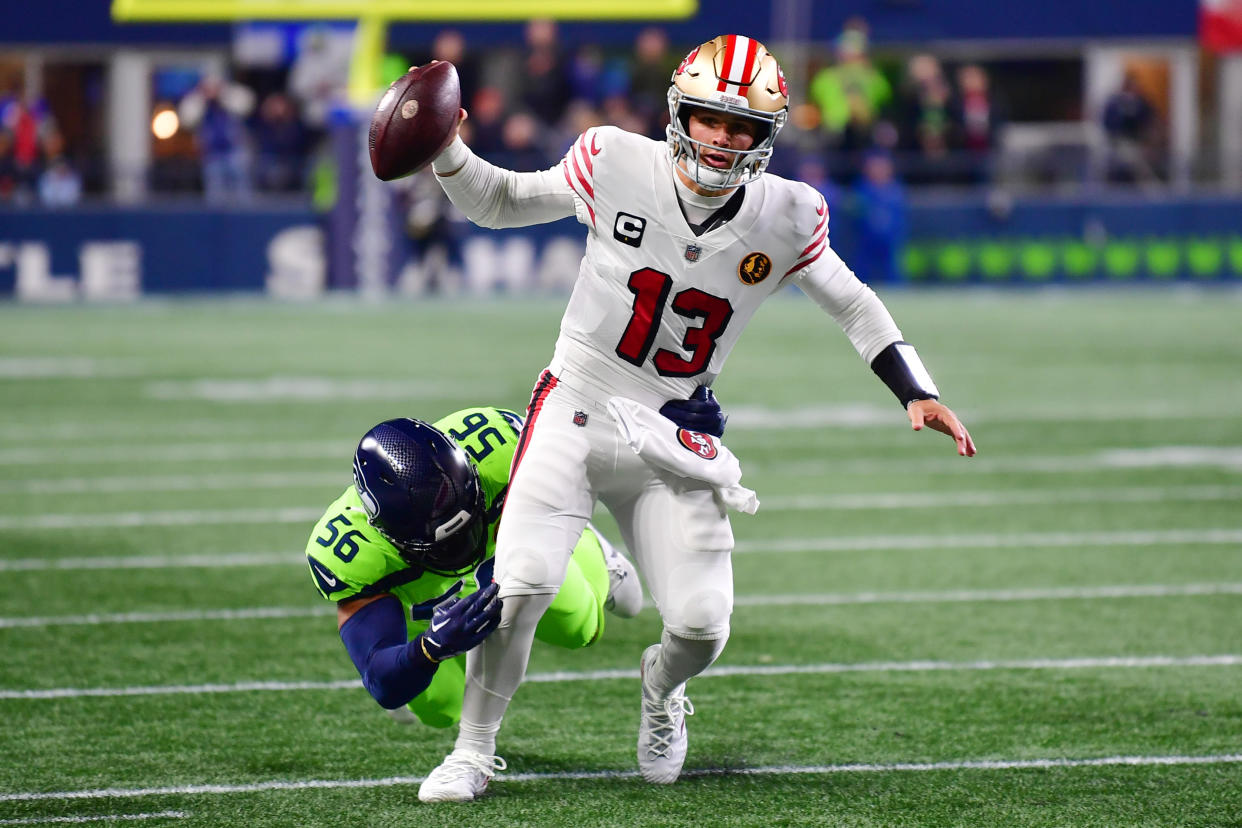 SEATTLE, WASHINGTON - NOVEMBER 23: Brock Purdy #13 of the San Francisco 49ers is tackled by Jordyn Brooks #56 of the Seattle Seahawks during the first quarter at Lumen Field on November 23, 2023 in Seattle, Washington. (Photo by Jane Gershovich/Getty Images)