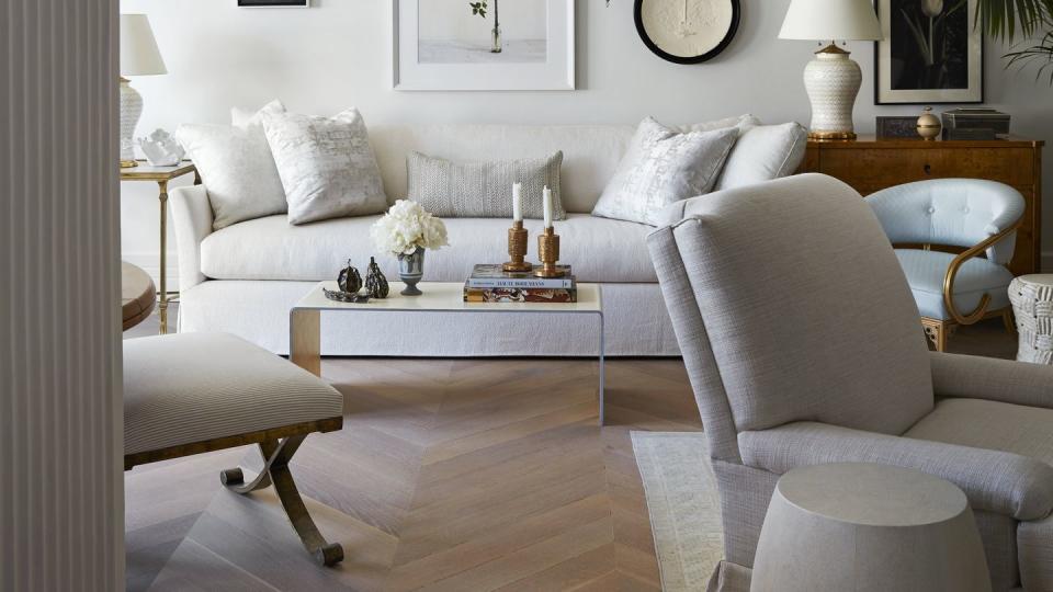 a pair of 19th century italian sconces flanks a still life painting by alec soth that hangs above a white sofa