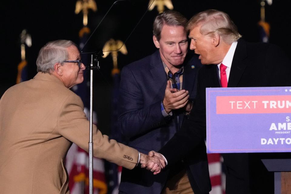 Former President Donald Trump greets Ohio Gov. Mike DeWine and Lt. Gov. Jon Husted during a rally at Wright Bros. Aero Inc. at Dayton International Airport on Monday.