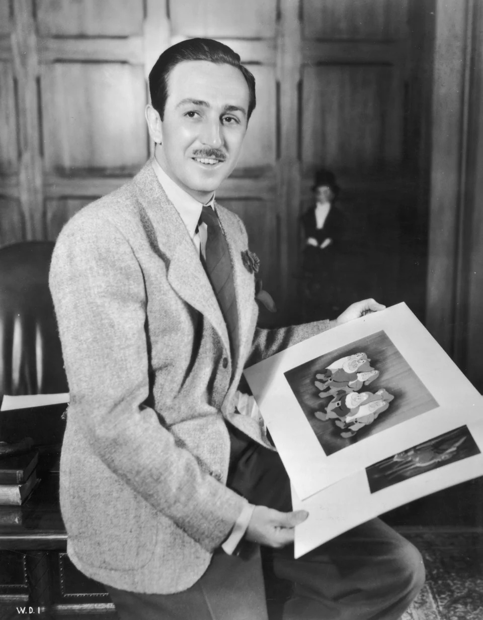 1942: Walt Disney (1901 - 1966) sostiene las ilustraciones de &#39;Snow White and the Seven Dwarfs&#39; and &#39;Bambi.&#39; Animator David Hand directed both films.  (Photo by Hulton Archive/Getty Images).