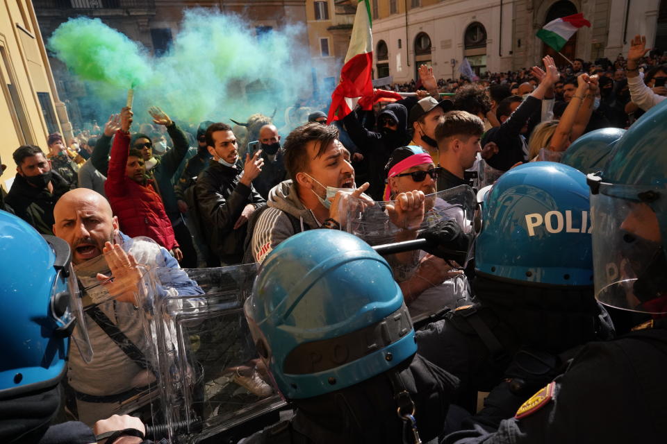 Demonstrators scuffle with Italian Policemen during a protest by Restaurant and shop owners outside the Lower Chamber in Rome, Tuesday, April 6, 2021. Demonstrators demanded to reopen their business and protested against restrictive measures of the Italian Government to cope with the surge of COVID-19 cases. (AP Photo/Andrew Medichini)