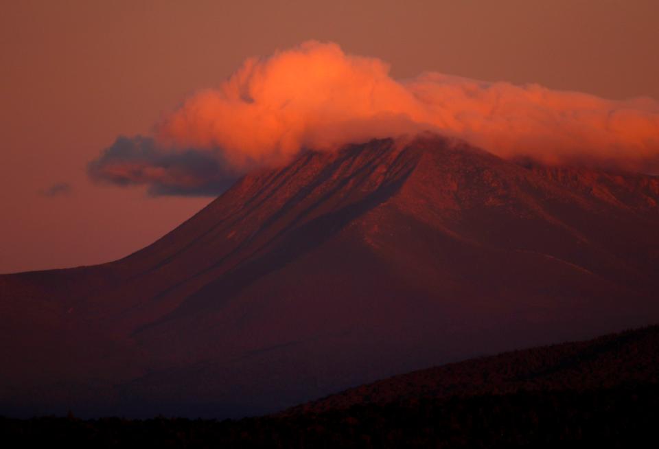 The first rays of sunlight color the clouds over Mount Katahdin in this view from Patten, Maine on Aug. 7, 2017.