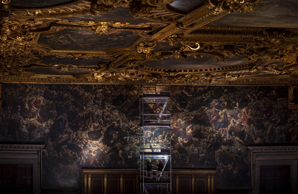 Architect Arianna Abbate, left, is interviewed by The Associated Press on a scaffolding used to inspect the 7,45x24,65-meter oil on canvas 'Il Paradiso' completed in 1592 by Venetian painters Jacopo Robusti, also known as Tintoretto, and his son Domenico in the Maggior Consiglio Hall inside Palazzo Ducale in Venice, northern Italy, Wednesday, Dec. 6, 2022. The Doge's Palace, the heart of the political life of the Venetian Republic for centuries, is undergoing a major reconnaissance of its conservation status by the Fondazione Musei Civici of the municipality of Venice that includes the urgent restoration of its paintings and infrastructures, which is expected to be completed in the summer of 2023. (AP Photo/Domenico Stinellis)