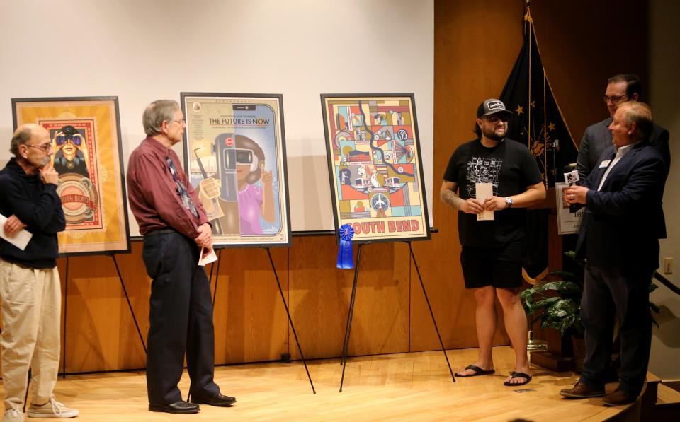 The three finalists for the “South Bend — The Next 100 Years” poster contest speak with museum officials after the winning posters were named in a ceremony Monday, Aug. 28, 2023, in the auditorium at The History Museum and Studebaker National Museum in South Bend. From left are finalists Steven Sult of Niles, who won second place; Bob Green of Scottsville, N.Y., who won third place; first-place winner Tyler Foley of South Bend; Brian Harding, executive director of The History Museum; and Patrick Slebonick, executive director of Studebaker National Museum.